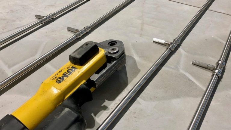 Kollane hüdrauliline pressseade metalltorude ja liitmike paigaldamiseks betoonpõrandal
