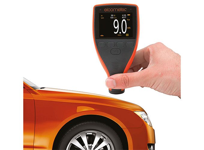 Käes hoitav Elcometer värvikihi paksuse mõõtja näiduga 9.0 mils oranži auto kere kohal