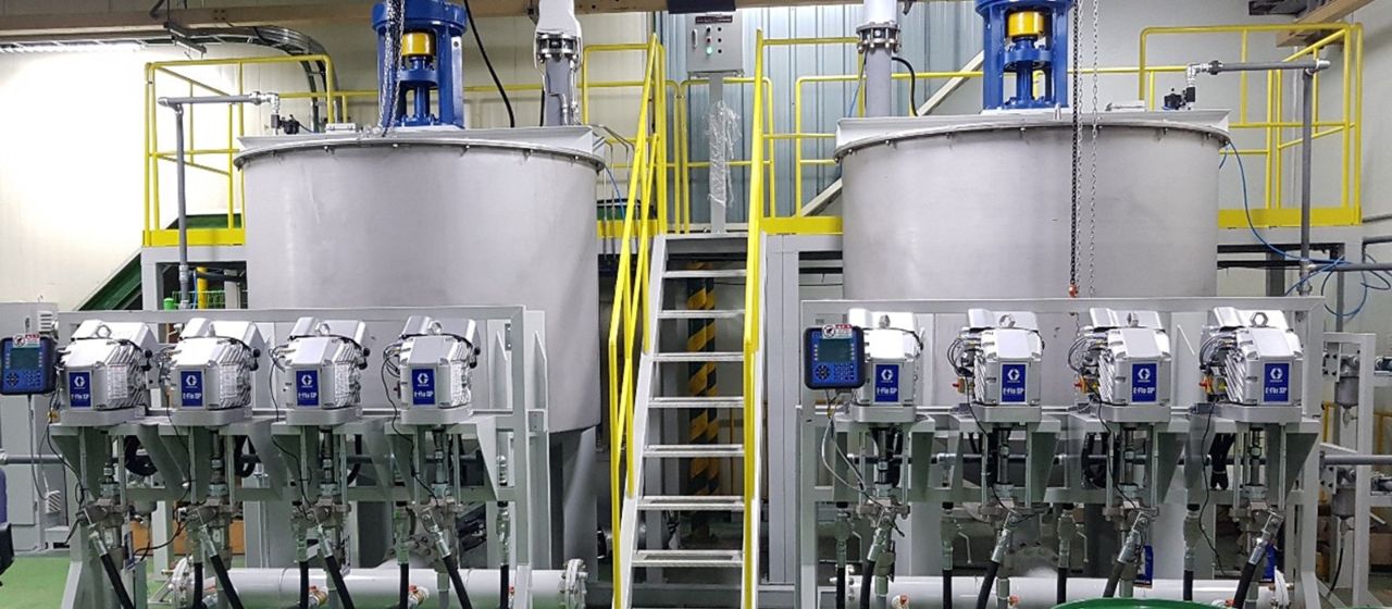 Graco E-Flo SP elektrilised värvipumbad kahe suure roostevabast terasest segamispaagi ees tööstushoones